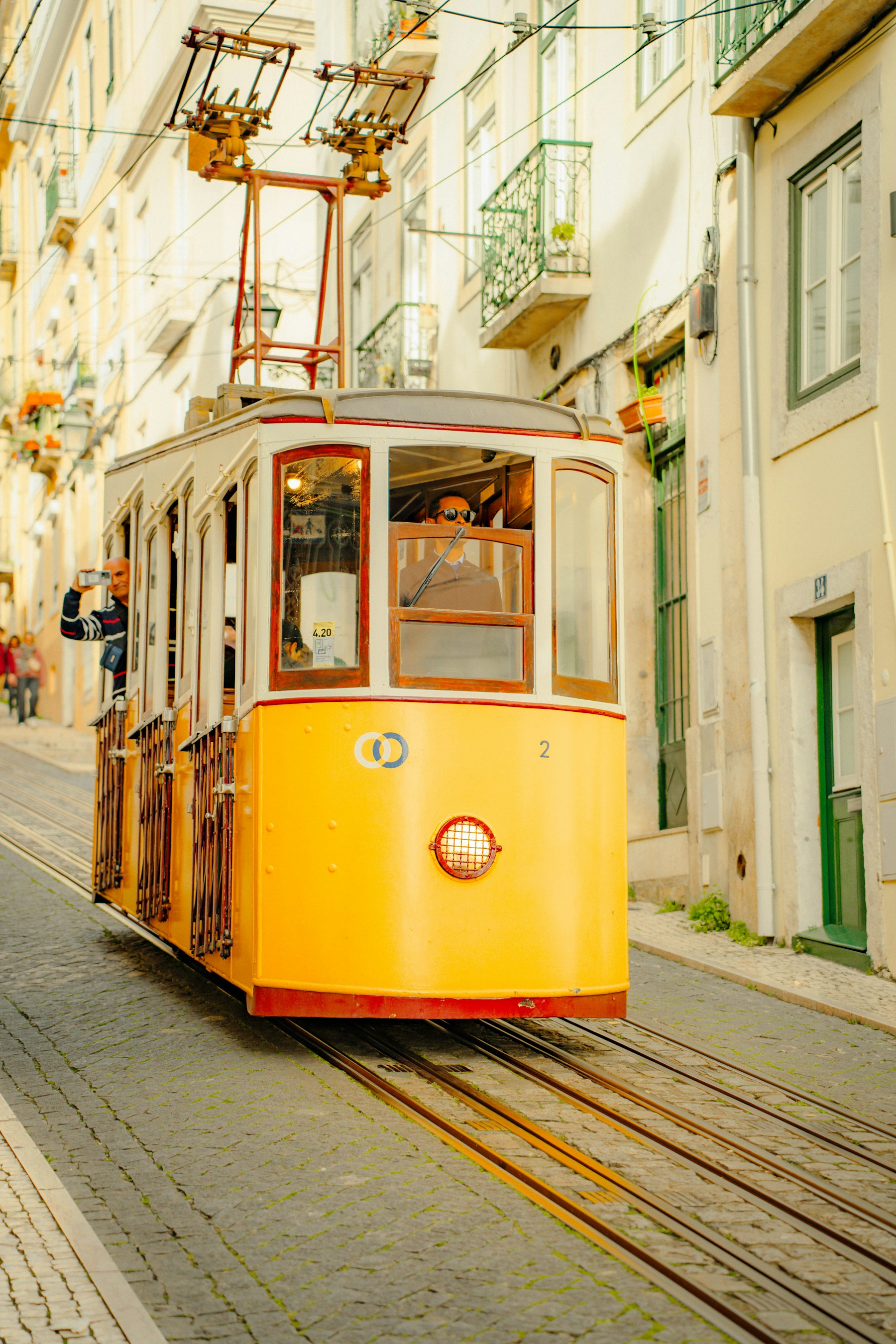 A classic yellow tram on a sunlit street in Lisbon